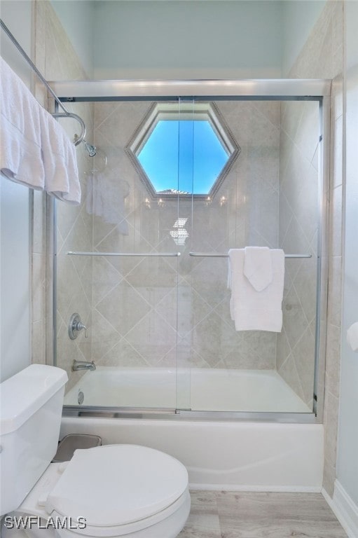 bathroom featuring hardwood / wood-style floors, toilet, and enclosed tub / shower combo