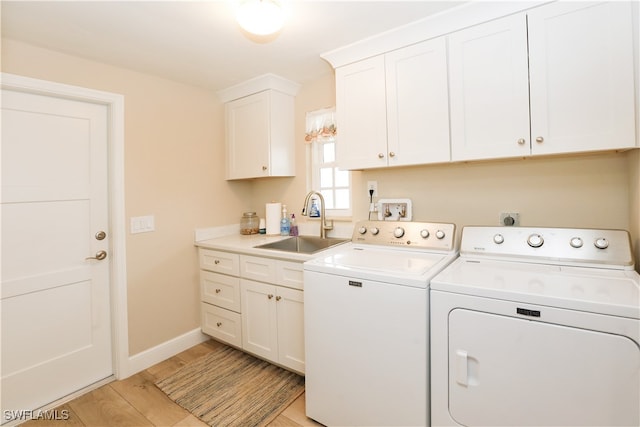 laundry area featuring sink, cabinets, light wood-type flooring, and washer and clothes dryer