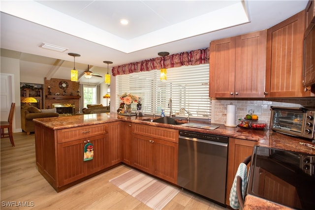 kitchen with light hardwood / wood-style flooring, dishwasher, decorative light fixtures, and a brick fireplace