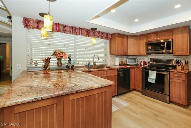 kitchen with light hardwood / wood-style flooring, hanging light fixtures, stainless steel appliances, sink, and light stone countertops