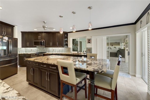 kitchen with appliances with stainless steel finishes, dark brown cabinets, ceiling fan, pendant lighting, and decorative backsplash