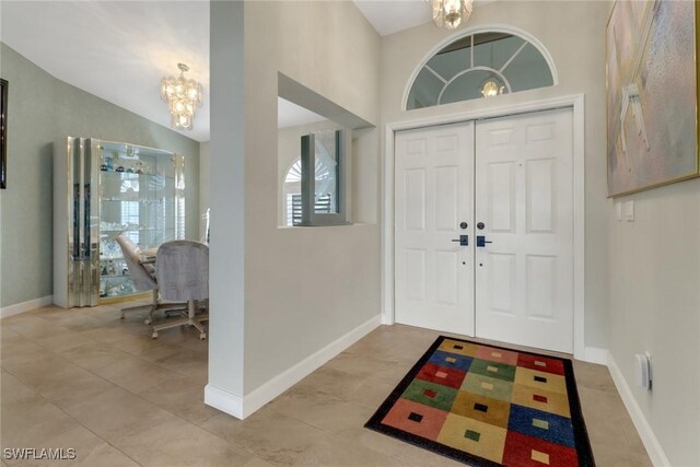 2822 SE 22nd Pl, Cape Coral, FL 33904 - foyer with baseboards, an inviting chandelier, light tile patterned floors, and a high ceiling