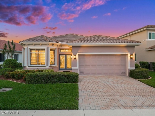 mediterranean / spanish home featuring a lawn and a garage