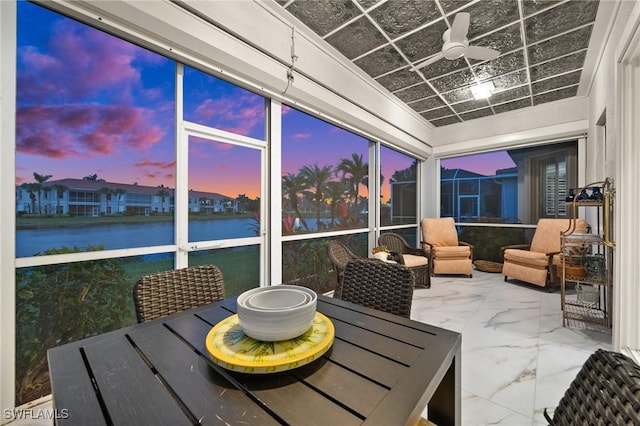 sunroom / solarium with ceiling fan and a water view