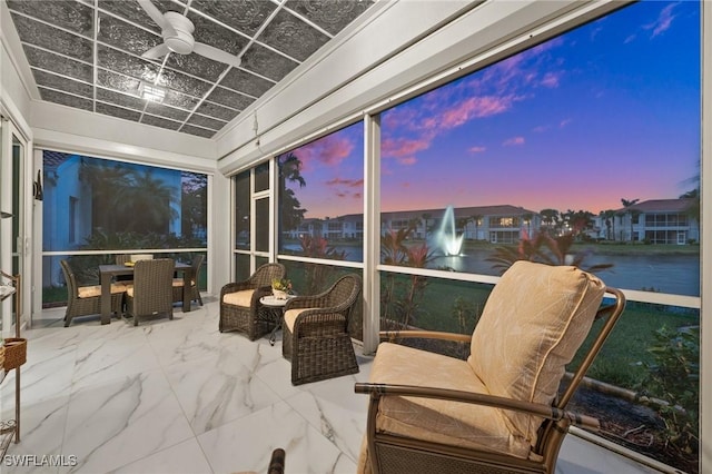 sunroom featuring ceiling fan and a water view