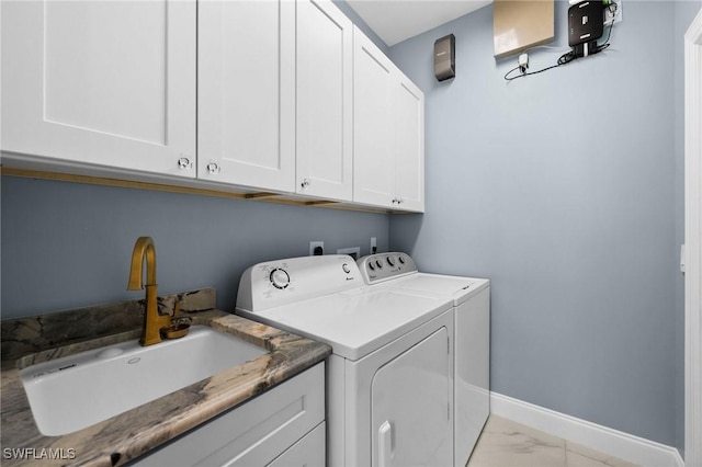 clothes washing area featuring washing machine and clothes dryer, cabinets, and sink