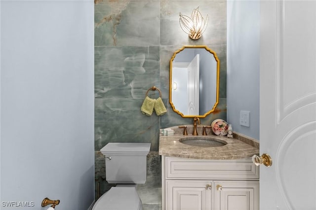 bathroom featuring vanity, toilet, and tile walls