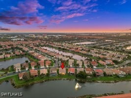 aerial view at dusk featuring a water view