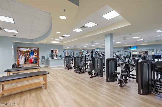 exercise room featuring light hardwood / wood-style flooring, a paneled ceiling, and a tray ceiling