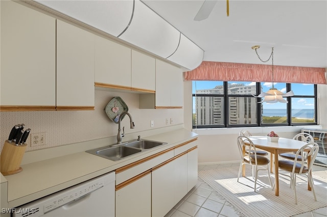 kitchen featuring white dishwasher, light tile patterned floors, a sink, light countertops, and white cabinets