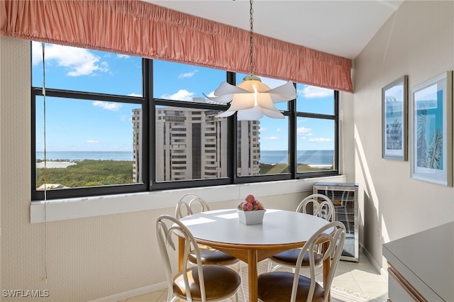 dining space with a water view, baseboards, and light tile patterned floors
