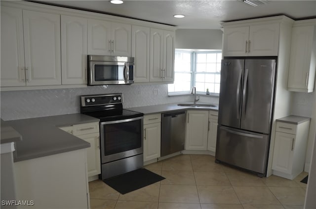 kitchen featuring light tile patterned floors, appliances with stainless steel finishes, sink, and white cabinets