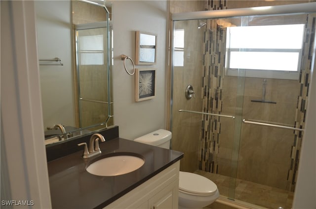 bathroom with toilet, vanity, and a shower with door