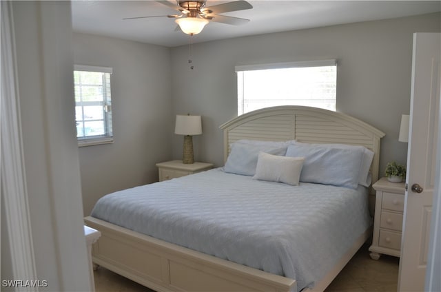 bedroom featuring ceiling fan, tile patterned floors, and multiple windows