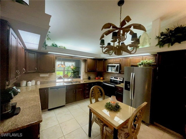 kitchen with backsplash, sink, light tile patterned floors, appliances with stainless steel finishes, and light stone counters