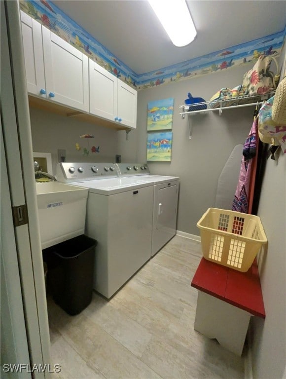 washroom featuring sink, washer and dryer, and cabinets