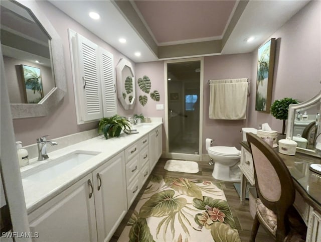 bathroom with hardwood / wood-style floors, a shower with door, a tray ceiling, toilet, and vanity