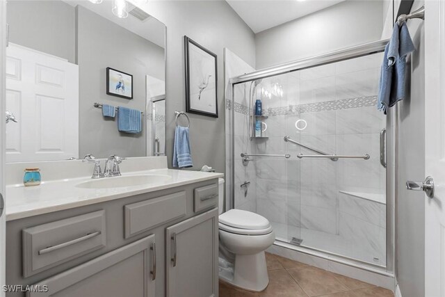 bathroom with vanity, toilet, a shower with shower door, and tile patterned flooring