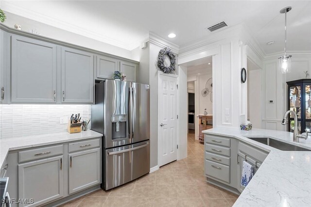 kitchen featuring light stone countertops, sink, stainless steel fridge, pendant lighting, and gray cabinets