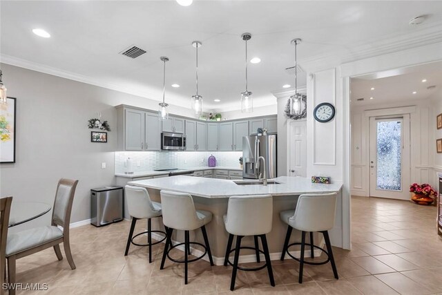 kitchen featuring decorative backsplash, hanging light fixtures, appliances with stainless steel finishes, a kitchen bar, and ornamental molding