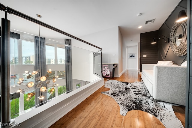 corridor with light hardwood / wood-style floors, plenty of natural light, and wooden walls