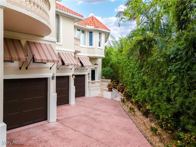 view of front of home with stucco siding, a tile roof, decorative driveway, and a garage