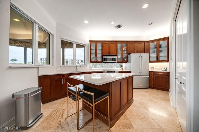 kitchen featuring visible vents, a kitchen island, light countertops, stainless steel appliances, and a sink