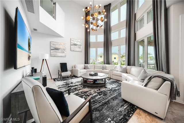 living room with an inviting chandelier, baseboards, visible vents, and a towering ceiling