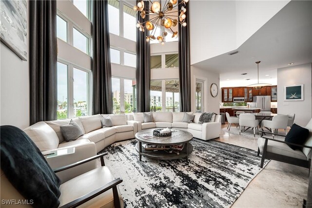 living room with a towering ceiling, concrete flooring, and an inviting chandelier