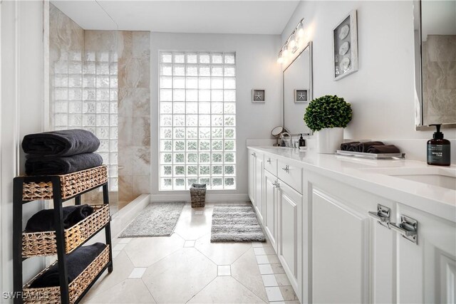 bathroom with tile patterned flooring, vanity, and tiled shower