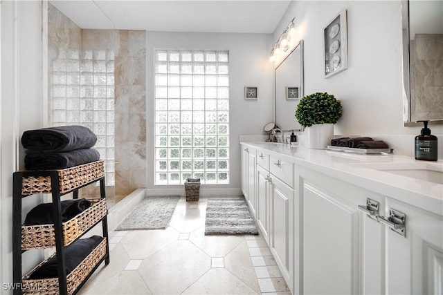 full bathroom featuring tile patterned flooring, double vanity, walk in shower, and a sink