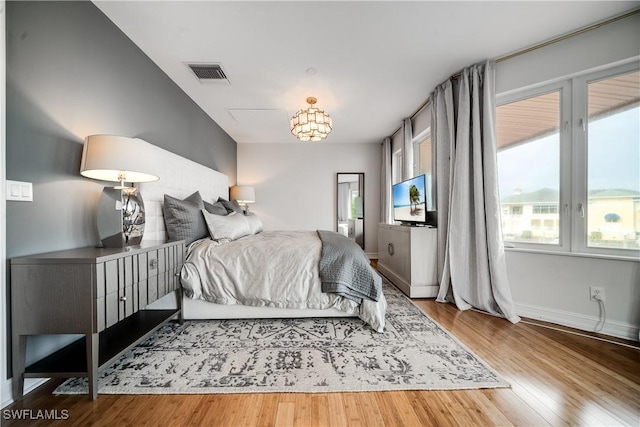 bedroom with wood finished floors, visible vents, and baseboards