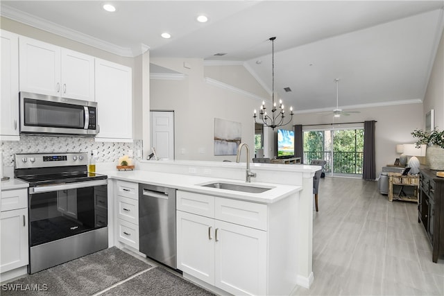 kitchen featuring appliances with stainless steel finishes, white cabinetry, vaulted ceiling, and sink