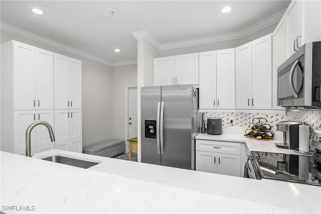 kitchen featuring appliances with stainless steel finishes, backsplash, light stone counters, sink, and white cabinets