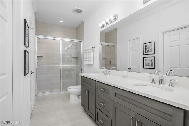 bathroom with vanity, toilet, a shower with shower door, and ornamental molding