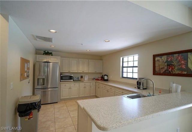 kitchen with light tile patterned flooring, kitchen peninsula, sink, and appliances with stainless steel finishes