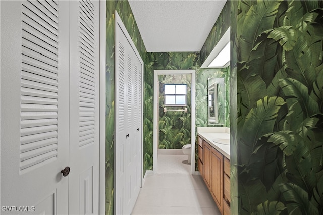 bathroom featuring toilet, vanity, a textured ceiling, and tile patterned floors