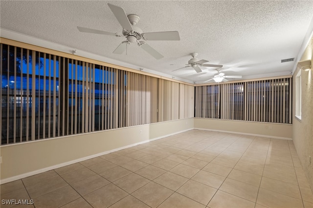 empty room featuring ceiling fan, a textured ceiling, and light tile patterned floors