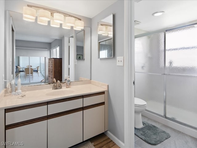 bathroom featuring vanity, toilet, and a shower with shower door