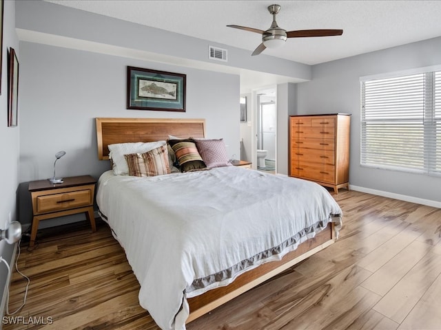 bedroom featuring a textured ceiling, hardwood / wood-style floors, ensuite bath, and ceiling fan