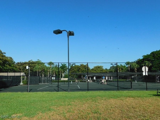 view of tennis court with a yard