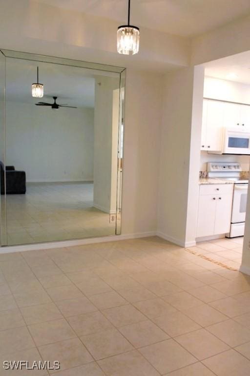 unfurnished dining area with light tile patterned flooring and ceiling fan