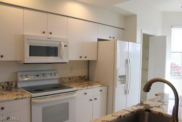 kitchen with sink, white appliances, white cabinetry, and light stone counters