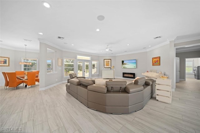 living room featuring plenty of natural light, ornamental molding, and ceiling fan