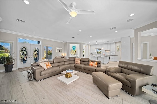 living room featuring a wealth of natural light, french doors, ceiling fan, and crown molding