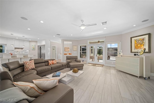 living room featuring ceiling fan, light wood-type flooring, and ornamental molding