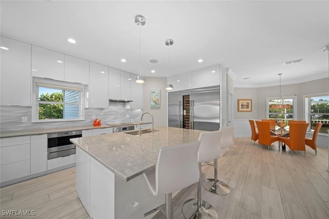 kitchen featuring white cabinets, sink, hanging light fixtures, a healthy amount of sunlight, and stainless steel appliances