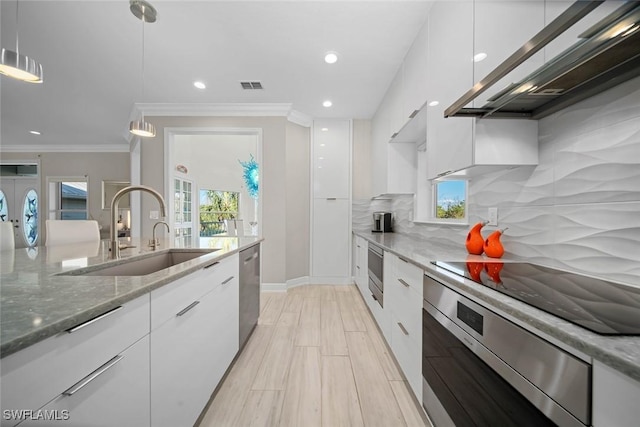 kitchen featuring backsplash, light stone counters, sink, pendant lighting, and white cabinetry