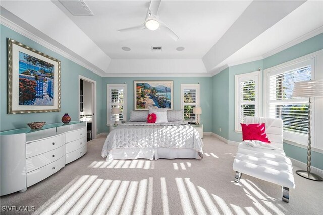 carpeted bedroom featuring ceiling fan, a raised ceiling, and ornamental molding