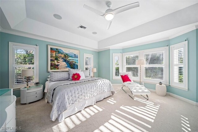 carpeted bedroom featuring ceiling fan, ornamental molding, and a tray ceiling